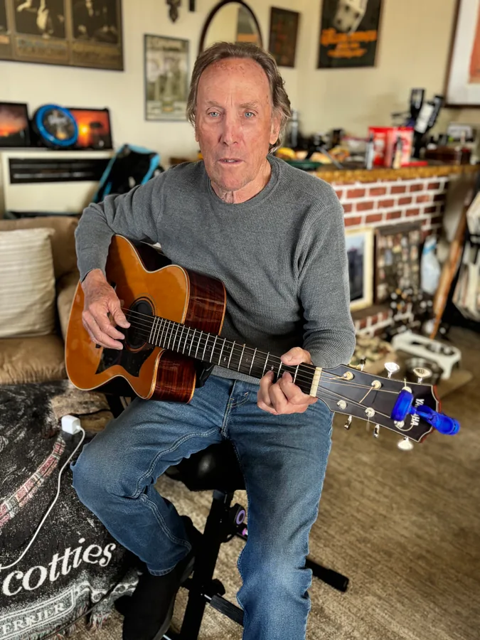 Steve Mackintosh seated with his acoustic guitar